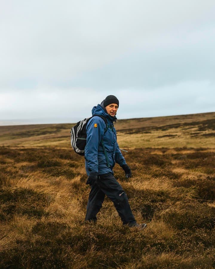 A man with a backpack walking across open ground.